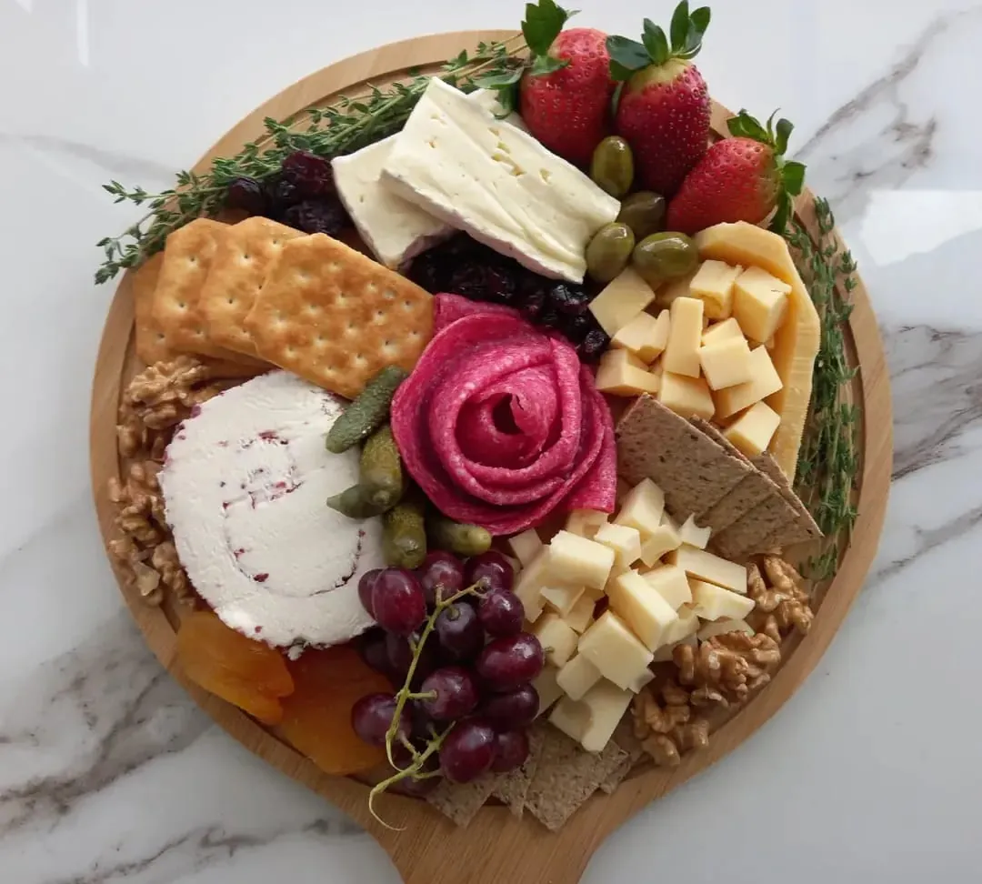 Board with salami rose, brie and walnuts